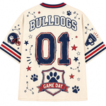 A cream-colored short-sleeve t-shirt shown from the back, featuring navy blue and red graphics. The design includes the word 'BULLDOGS' in arched letters, the number '01' in a distressed navy font, paw prints, stars, a football helmet, a megaphone, and a 'GAME DAY' banner at the bottom.
