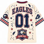 Back view of a cream-colored sports jersey with 'EAGLES' and '01' printed in navy blue with red outlines, featuring a team crest and 'GAME DAY' graphic on the lower back.