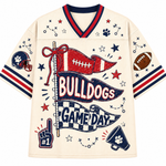 A cream-colored football jersey with red and navy blue trim, featuring a 'BULLDOGS GAME DAY' graphic with football-themed illustrations on a plain white background.