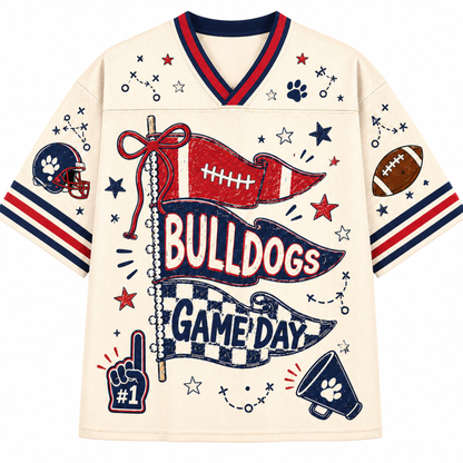 A cream-colored football jersey with red and navy blue trim, featuring a 'BULLDOGS GAME DAY' graphic with football-themed illustrations on a plain white background.