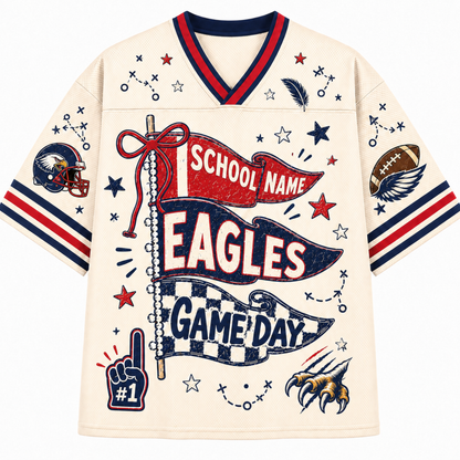 A cream-colored short-sleeve V-neck jersey with red and navy blue trim, featuring a large patriotic football graphic on the front with the words 'School Name Eagles Game Day' and various sports-themed illustrations.