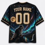 A custom short-sleeve t-shirt with a black base, featuring a detailed graphic print of a raccoon overlooking a waterfall and forest under a starry night sky with aurora lights. The shirt includes customizable text 'YOUR NAME' and '00' on the front.