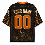 A black short-sleeve t-shirt with a Halloween-themed graphic print, featuring 'YOUR NAME' and '00' in orange block letters on the back, surrounded by pumpkins, a haunted house, bats, and a crescent moon.