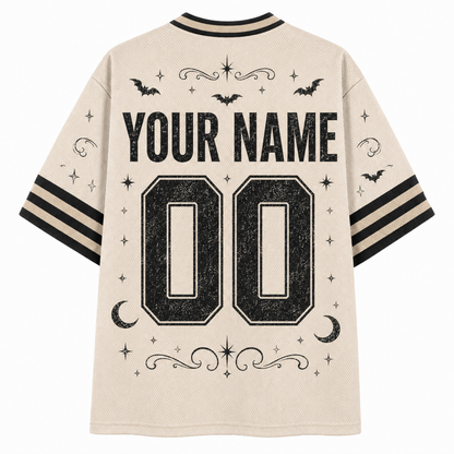Back view of a cream-colored mesh short-sleeve jersey with black graphic prints including 'YOUR NAME', '00', bats, moons, stars, and stripes on the sleeves.