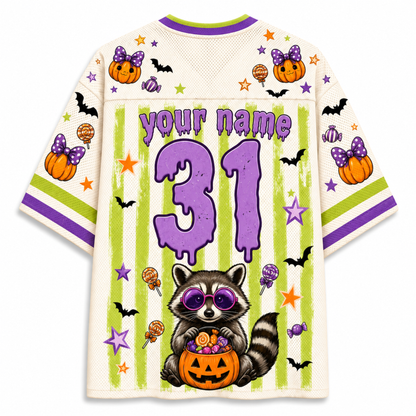 A Halloween-themed short-sleeve jersey shirt shown from the back, featuring a cream mesh base with purple and lime green graphics. The design includes the text 'your name', the number '31' in purple, a raccoon holding a jack-o'-lantern, bats, pumpkins, stars, and candy motifs.