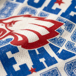 Close-up of a white textured sports jersey with a large red and white animal head graphic and bold blue lettering, including a red star.