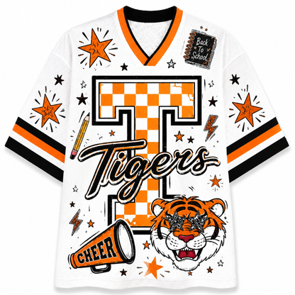 A white short-sleeve V-neck jersey with orange and black stripes on the sleeves, featuring a large orange and black checkered 'T' with 'Tigers' script across the front, plus a tiger face, megaphone, stars, and a 'Back to School' notebook graphic.