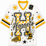 A white V-neck athletic jersey with yellow and black graphics, featuring a large checkerboard 'H', the word 'Hornets', stars, lightning bolts, a bee, and a megaphone on the front.