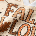 Close-up of a cream-colored mesh fabric with a 'FALL' word design in brown and orange, featuring polka dots, gingham, and solid textures, alongside a brown leaf motif.