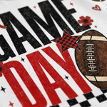 Close-up of a white fabric surface printed with large black and red text, a brown football graphic, and small red flowers and stars.