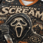 Close-up of a black graphic T-shirt featuring the Ghostface mask from Halloween, with distressed cream lettering reading 'HALLOWEEN SCREAM' and spooky illustrations including a haunted house and 'TRICK OR TREAT'.