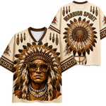 A cream-colored short-sleeve V-neck jersey shirt shown from both front and back, featuring a large Native American warrior portrait with a feathered headdress and the words "WARRIOR SPIRIT" on the back.