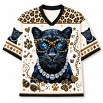 A short-sleeve V-neck graphic shirt featuring a large black panther illustration with blue eyes, leopard-print shoulder panels, paw prints, sunglasses, chain motifs, and a jeweled necklace design on an off-white background.