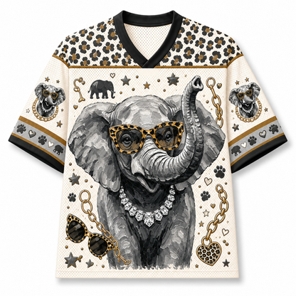 A short-sleeve V-neck t-shirt featuring a detailed graphic print of a gray elephant wearing leopard-print sunglasses and a diamond necklace, surrounded by gold chains, paw prints, and elephant heads on a cream background.