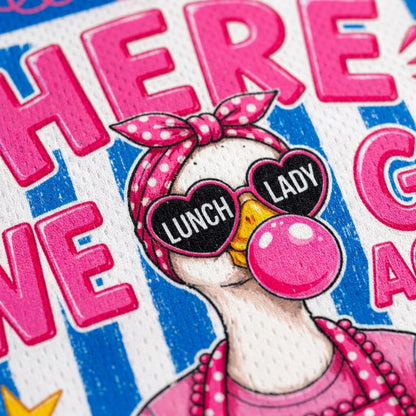 Close-up of a colorful printed graphic featuring a cartoon duck wearing pink polka-dot sunglasses with the words 'LUNCH LADY' on the lenses, a pink polka-dot bow headband, and a pink bubblegum bubble against blue-and-white striped lettering.