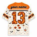 A short-sleeve football-style jersey shown from the back, with orange shoulder panels, a cream body, and Halloween-themed graphics including the number 13 filled with jack-o'-lantern faces, stars, bats, dots, and pumpkins. The top reads 'your name' in script, indicating a customizable design.