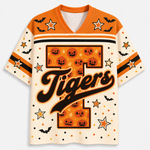 A short-sleeve V-neck jersey with a Halloween theme, featuring an orange and cream color palette. The front displays a large number '1' filled with jack-o'-lanterns and the word 'Tigers' in black script with an orange outline.