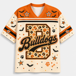 Front view of the cream varsity jersey displaying a large plaid monogram letter with script 'Bulldogs' text surrounded by black bats and pumpkin doodles.