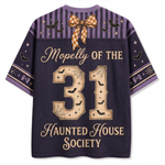 A short-sleeve t-shirt with a Halloween-themed graphic on the back. The shirt is dark purple with a purple and gold striped yoke decorated with a checkered bow, bats, and stars.