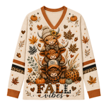 A long-sleeve V-neck sweater with a cream base and a detailed autumn graphic featuring three stacked Highland cows, pumpkins, leaves, acorns, and the text 'Fall vibes'.