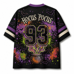 A black short-sleeve t-shirt with a vibrant Halloween-themed graphic on the back. The design features the words 'Hocus Pocus' in a stylized font above a large '93' and a cauldron with purple, orange, and green splatters and stars.