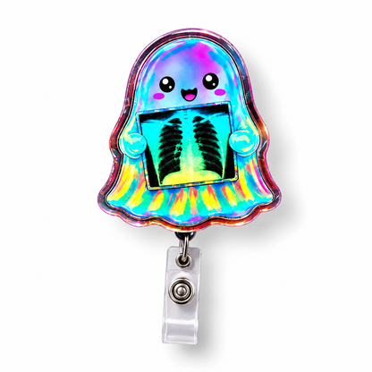 A ghost-shaped retractable badge reel with a holographic rainbow finish and a cute smiling face holding an X-ray graphic, attached to a clear plastic clip on a white background.