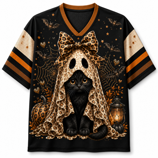 A black short-sleeve V-neck jersey-style shirt with a large Halloween graphic of a black cat under a leopard-print bow and spiderweb cloak, plus pumpkins, bats, stars, and a lantern. The sleeves have beige mesh panels with black and orange stripes.