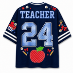 A navy blue short-sleeve t-shirt shown from the back, featuring 'TEACHER' and the number '24' in a blue-and-white gingham pattern. The shirt is decorated with a red polka-dotted apple, pencils, flowers, bows, and a ribbon on the sleeves and back.