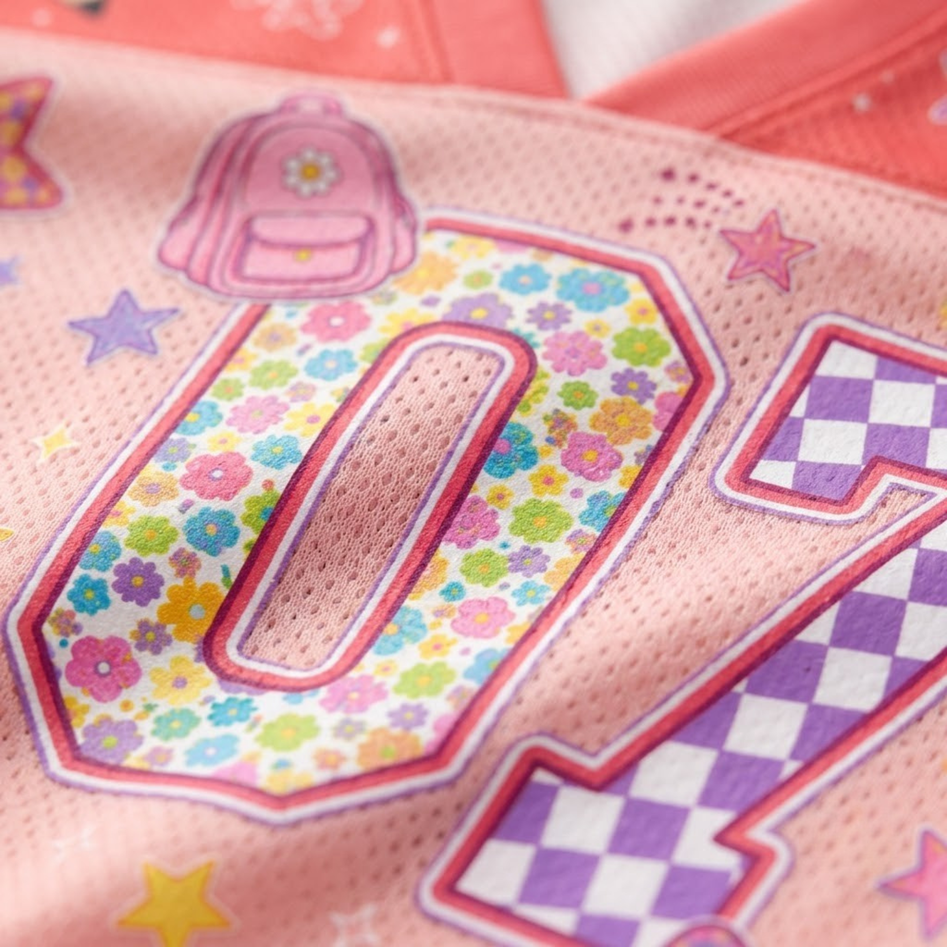 Macro close-up shot of the graphic print on mesh fabric, focusing on the high-definition textures of the floral pattern number 01 and pink checkerboard star details.