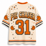 Back view of a cream-colored Pie Chaser 31 jersey with orange and black accents, featuring a retro football theme with stars, stripes, and Pac-Man graphics.