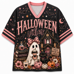 A black short-sleeve V-neck t-shirt with pink trim and a detailed Halloween graphic. The graphic features the text 'HALLOWEEN vibes' in pink, a haunted house, a ghost holding a coffee cup, a black cat, pumpkins, flowers, stars, and moons.