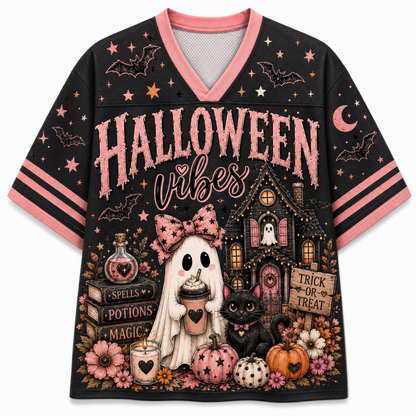 A black short-sleeve V-neck t-shirt with pink trim and a detailed Halloween graphic. The graphic features the text 'HALLOWEEN vibes' in pink, a haunted house, a ghost holding a coffee cup, a black cat, pumpkins, flowers, stars, and moons.