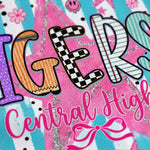 A close-up of a decorative printed design with the word "TIGERS" in large stylized letters and the phrase "Central High" in pink script below, on a bright pink, blue, white, and black patterned background.