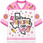 A white and pink V-neck graphic t-shirt featuring the text 'She's a PRINCIPAL I can tell' in a playful font, surrounded by school-themed doodles like pencils, flowers, stars, and a drink cup.