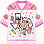 A girls' V-neck t-shirt with a white body and pink sleeves/collar, decorated with colorful cartoon graphics including smiley-face flowers, pencils, stars, and the text 'She's an INSTRUCTIONAL COACH I can tell'.