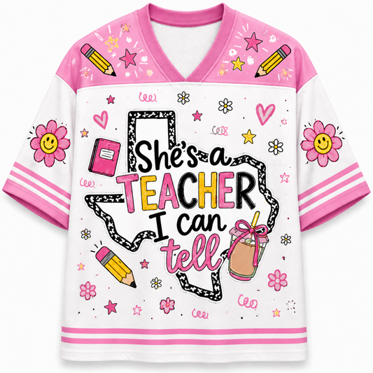 A women's short-sleeve V-neck t-shirt with a white body and pink sleeves, decorated with school-themed graphics including pencils, flowers, stars, and the text 'She's a TEACHER I can tell'.