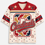 A short-sleeve V-neck jersey-style shirt with a cream base, red shoulder panels, navy and gold stripes, star motifs, bird head graphics on the shoulders, and a large camouflage-style letter C with the word 'Cardinals' across the front. The design resembles a sports team jersey, likely Arizona Cardinals themed.