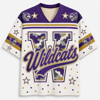 A short-sleeve V-neck jersey-style shirt with a white base, purple and gold trim, a large outlined letter W with camouflage fill, the word 'Wildcats' across the front, and wildcat head graphics near the shoulders with star accents.