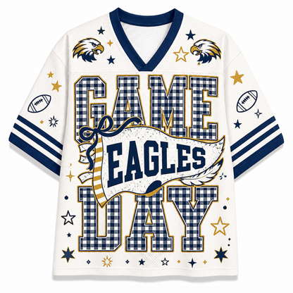 A white short-sleeve football jersey with navy blue and gold graphics celebrating 'Game Eagles Day'. The jersey features a navy blue V-neck collar, navy and gold gingham patterned block letters spelling 'GAME EAGLES DAY', eagle head illustrations, football motifs, and gold stars.