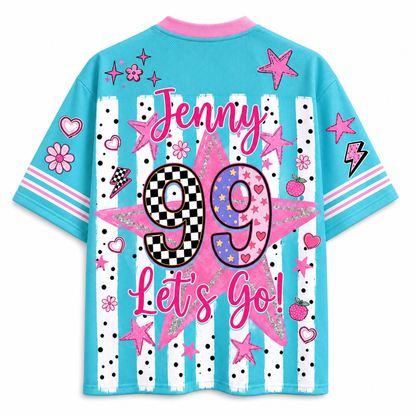 A light blue short-sleeve t-shirt with a vibrant pink and white graphic design on the back. The design features the text 'Jenny 99 Let's Go!' in pink script and block lettering, decorated with pink stars, hearts, flowers, and a checkerboard pattern inside the number 99.