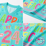 A close-up collage of a turquoise V-neck T-shirt showing colorful printed text and graphics. The shirt features large multicolored letters spelling parts of a phrase, star and smiley-face motifs, and a large pink outlined number 24 with star details.