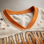 Close-up of a white mesh V-neck jersey with an orange ribbed collar, orange and black star details, and a large distressed orange 'HALLOWEEN' graphic across the front.