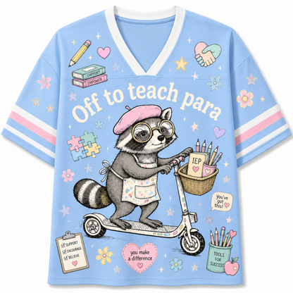 A light blue V-neck short-sleeve t-shirt with a cartoon raccoon riding a scooter, wearing a pink beret and apron. The shirt features the text 'Off to teach para' and various cute school-themed illustrations including a pencil, books, flowers, and a basket of pencils.