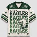 A short-sleeve V-neck football jersey with a cream mesh body, dark green shoulders, and green and cream graphics. The front features the words 'let's go EAGLES EAGLES EAGLES EAGLES EAGLES' in large green block letters, a large eagle head graphic, and star details on the sleeves and shoulders.