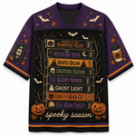 A purple and black short-sleeve V-neck t-shirt with a detailed Halloween graphic on the front. The graphic features a stack of horror movie book spines with titles like 'The Witching Hour' and 'Haunted Hollow', surrounded by bats, pumpkins, and the text 'spooky season'.