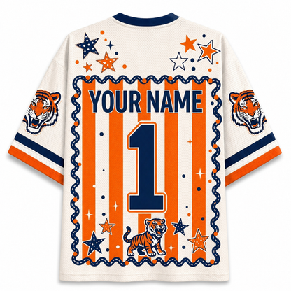 Customizable short-sleeve jersey shirt shown from the back, featuring orange and navy blue vertical stripes, a large navy number 1, 'YOUR NAME' text, tiger graphics on the sleeves and lower back, and star motifs on a white mesh background.