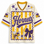 A cream-colored short-sleeve jersey with purple and yellow graphics, featuring the word 'Hornets' in large script, stars, stripes, a bow, and a hornet illustration on the front.