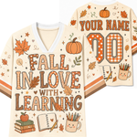 Front and back views of a custom football-style V-neck shirt in cream with orange and brown autumn-themed graphics, including pumpkins, leaves, stars, books, an apple, a notebook, a pencil cup, and large customizable text reading 'FALL IN LOVE WITH LEARNING' on the front and 'YOUR NAME 00' on the back.