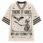 A cream-colored athletic-style t-shirt with black graphic prints of a skeleton, bats, stars, and the text 'THERE IT GOES, MY LAST FLYING F*CK' on a plain white background.