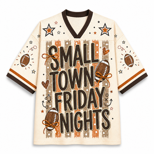 A cream-colored football jersey with 'SMALL TOWN FRIDAY NIGHTS' printed in bold black letters over brown and orange stripes on the front. The jersey features brown and black trim, star graphics, and football illustrations on the sleeves and front.